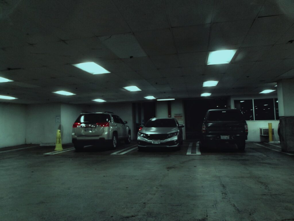 A parking garage with two cars parked in it
