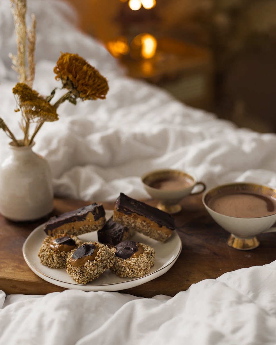 A tray of food on a bed with a vase of flowers