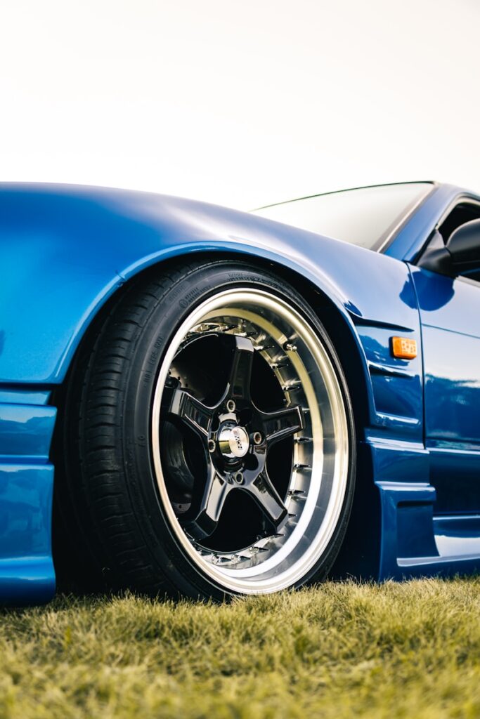 Close-up of a shiny blue car wheel on grass